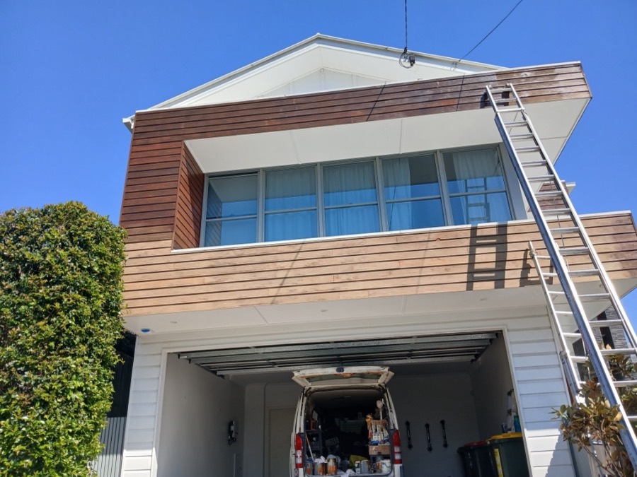 Exterior repaint in progress with ladder access on a two-storey home