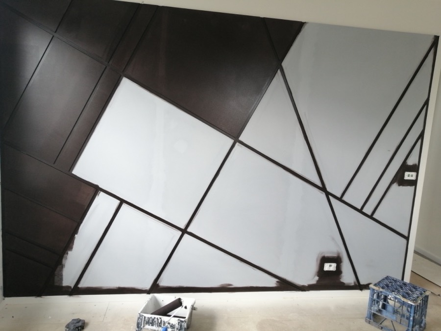 Geometric feature wall mid-project, dark panels and taped lines